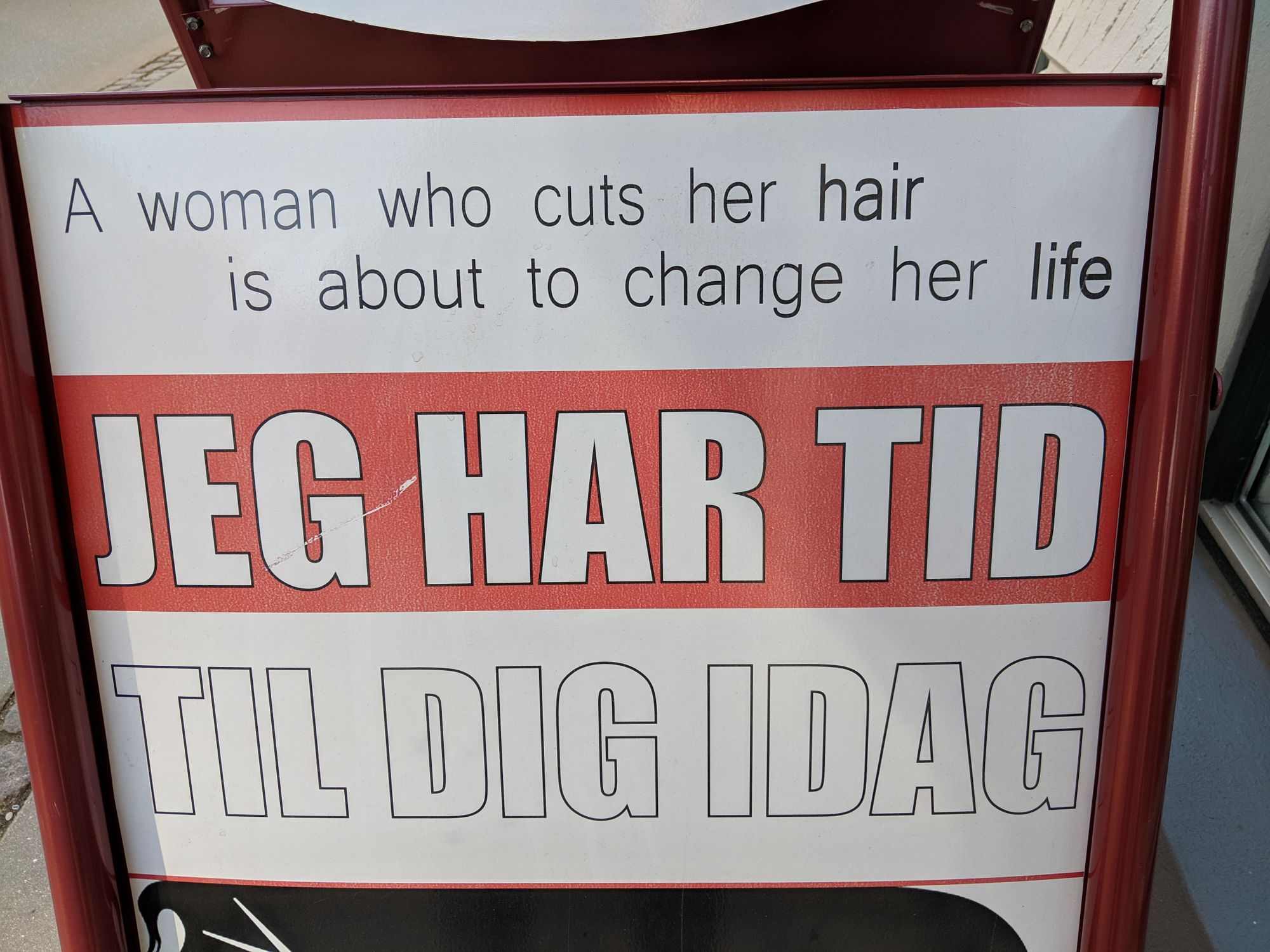 Sign outside a hair salon. 'A woman who cuts her hair is about to change her life', it says.