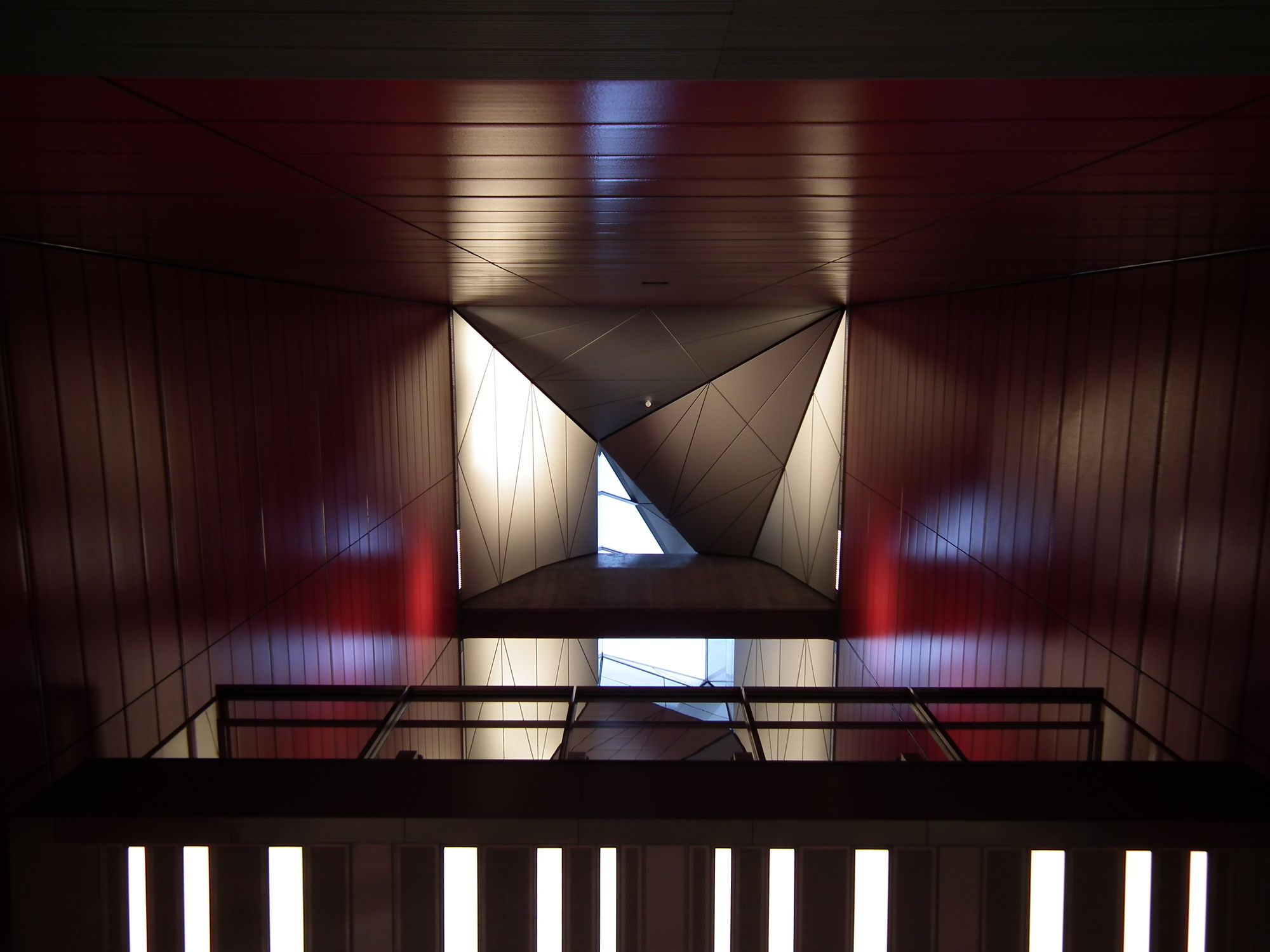 Looking directly up. An interesting mixture of black, white (lighting / sunlight), red, and a kind of gold hue.