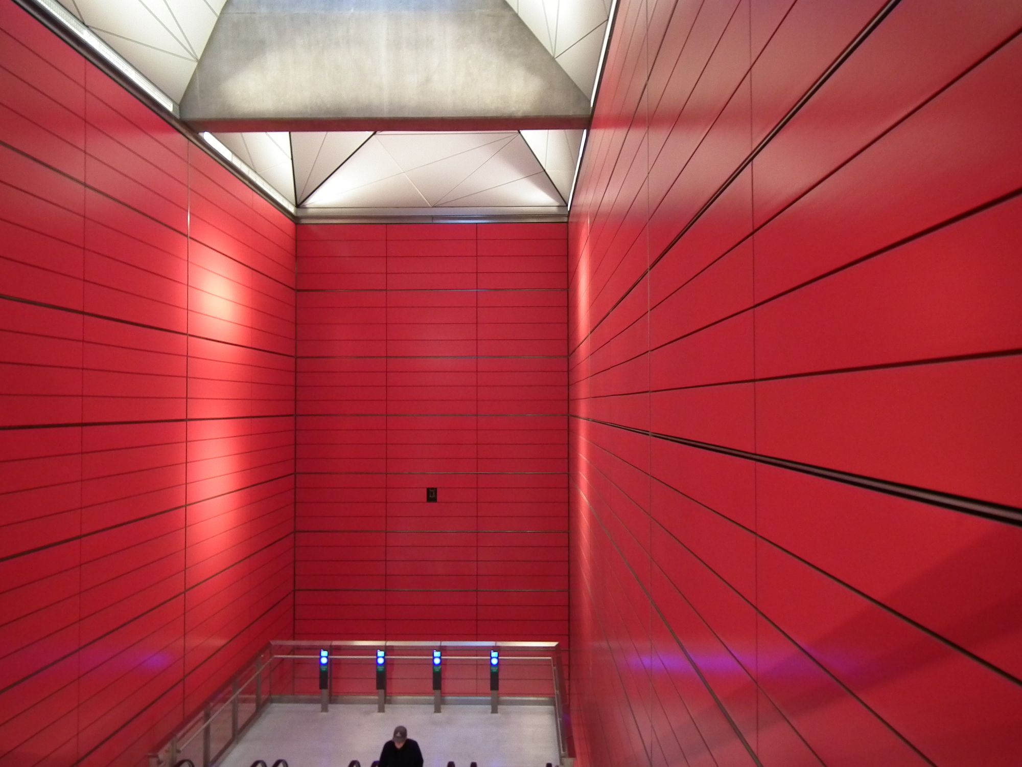The station well, brightly-lit, showing the two side and one end wall, covered in bright uniformly-red panels.