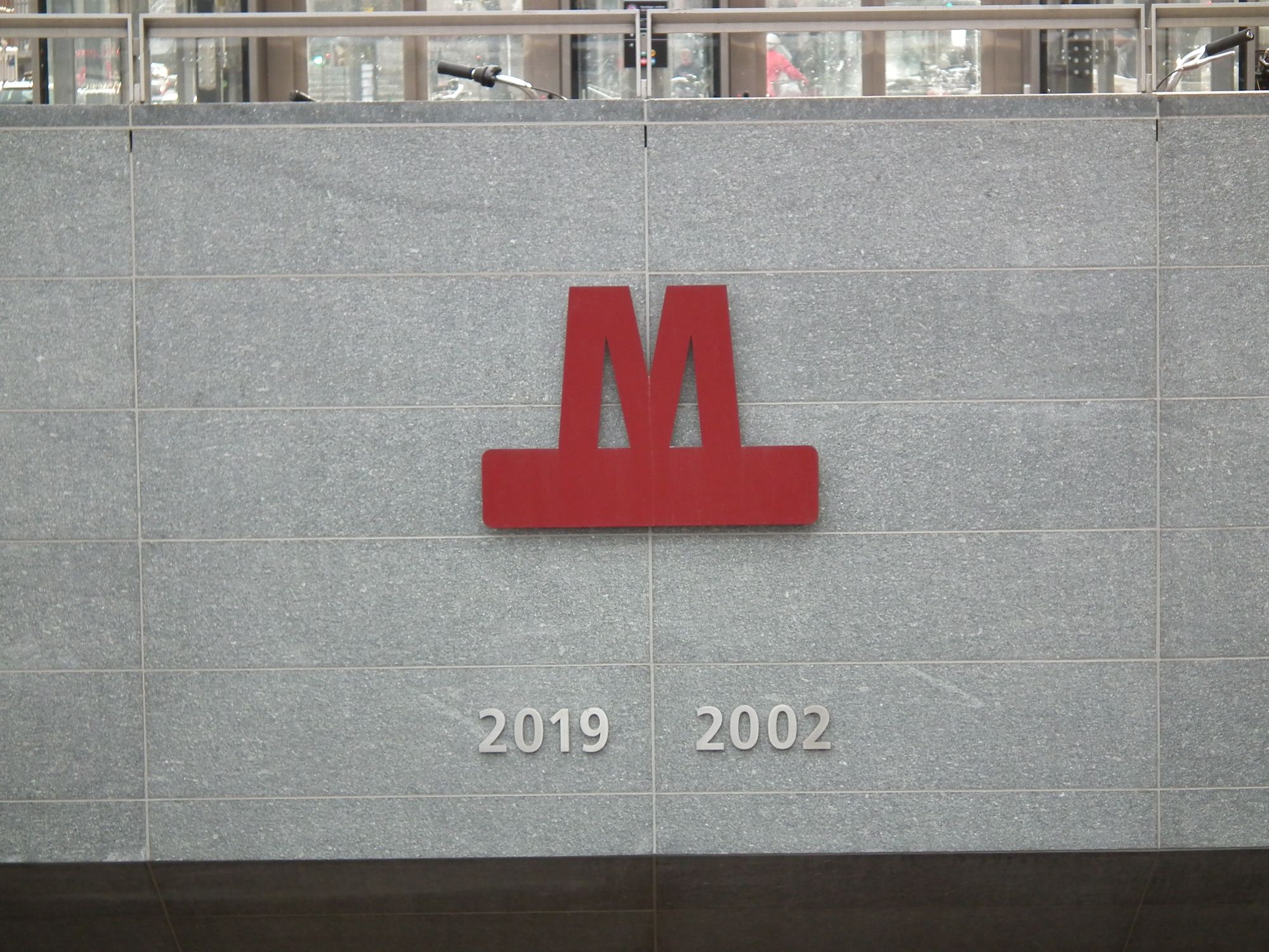 Above the entrance to the station, the 'M' metro logo, and the years of opening: 2019 (for M3/M4) and 2002 (for M1/M2).