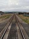 A single track of railway, stretching in a very straight and level line, directly away from the camera. We are stood on an unprotected level crossing. It's a grey, cloudy December day on the west coast of Wales.